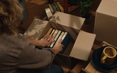 Relocation, prepare for move. Female hands packing books in moving box.